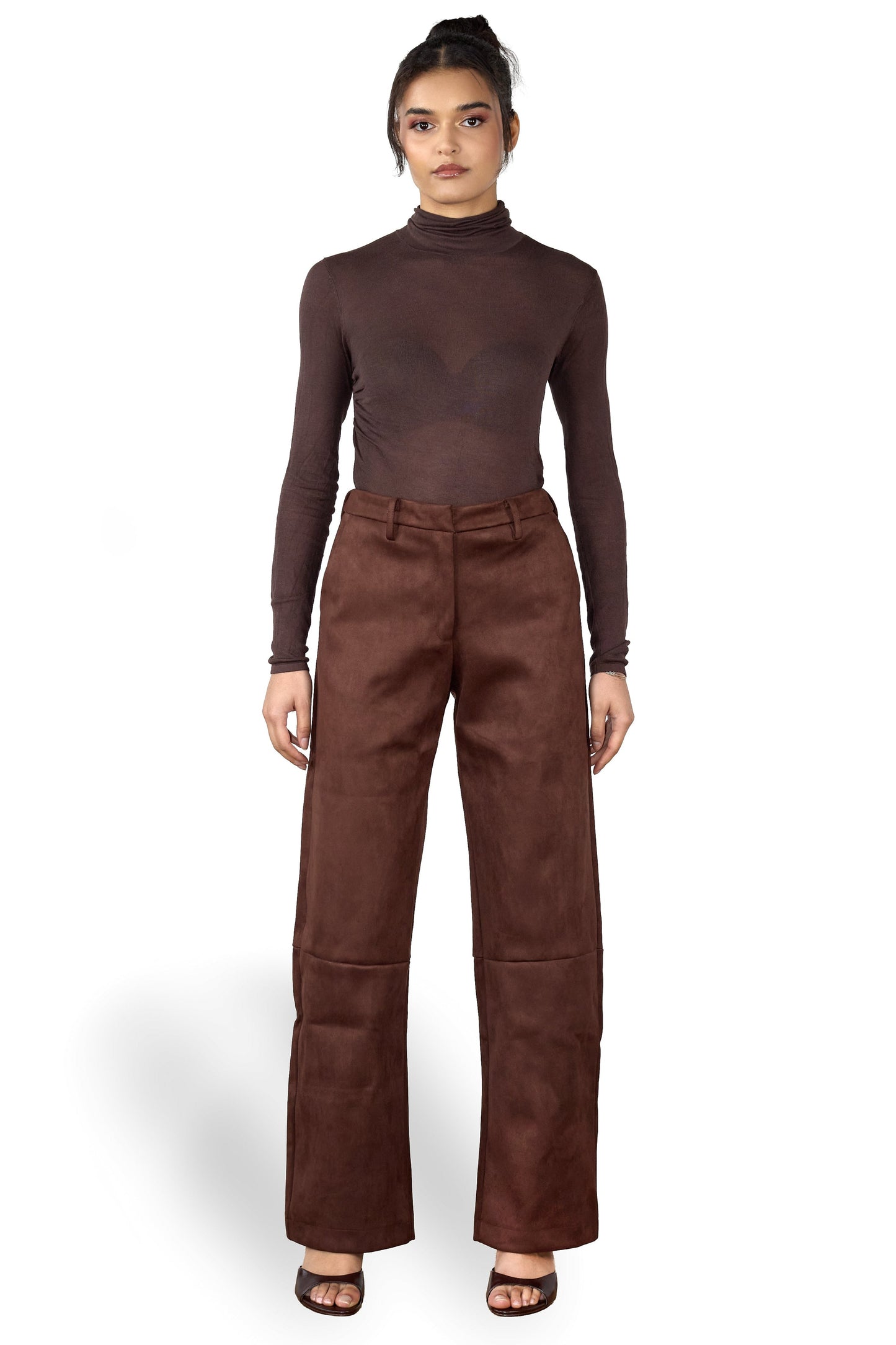 Woman wearing a brown turtleneck and wide-leg brown suede pants on a white background