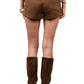 Person wearing brown suede shorts and boots on a plain background