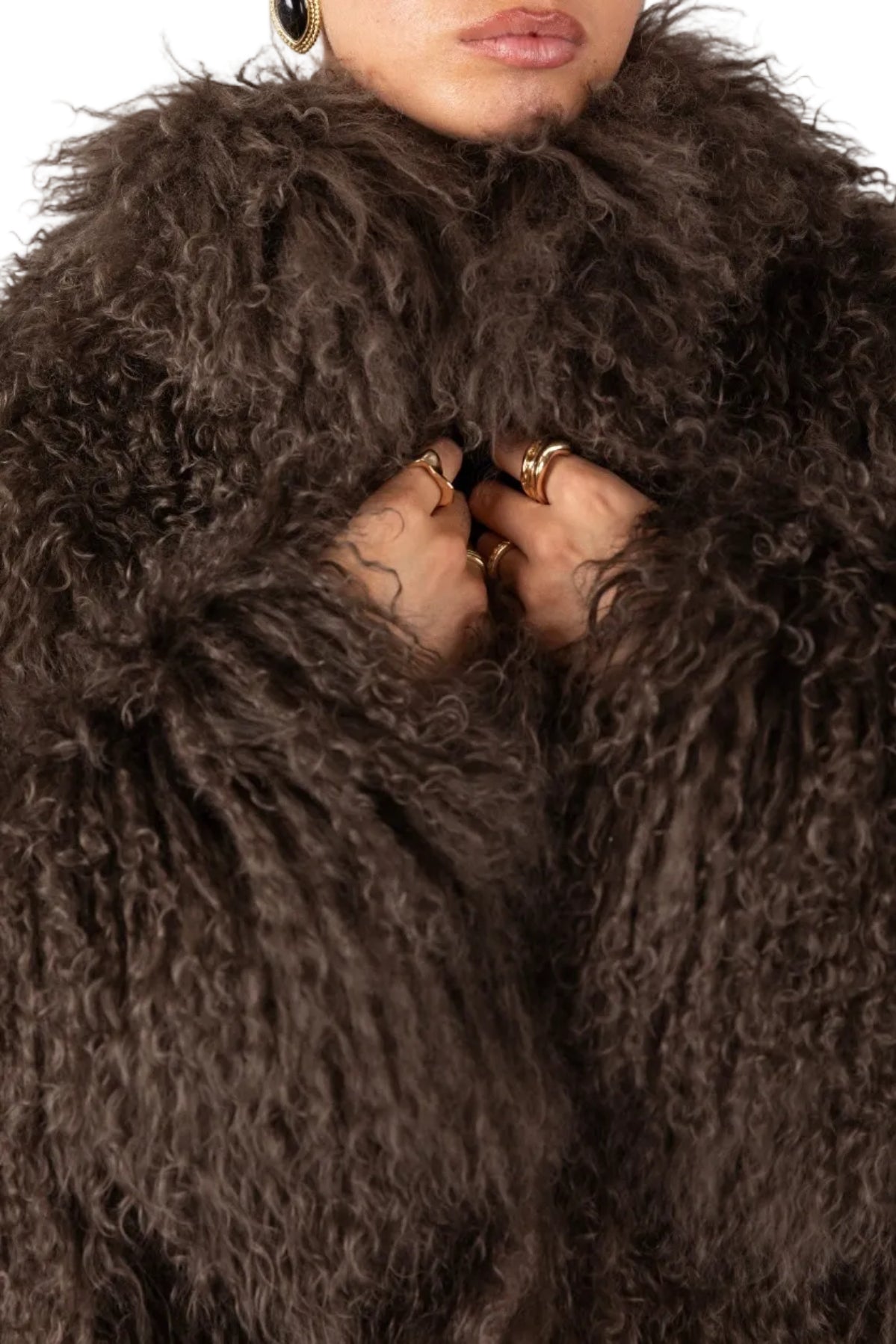 Close-up of a person wearing a brown Mongolian fur coat  with a neutral background