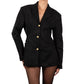 Woman wearing a black blazer with gold buttons on a white background
