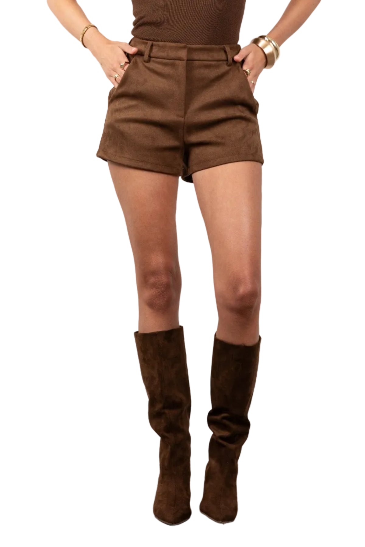 Person wearing brown high-waisted shorts and knee-high boots on a plain background