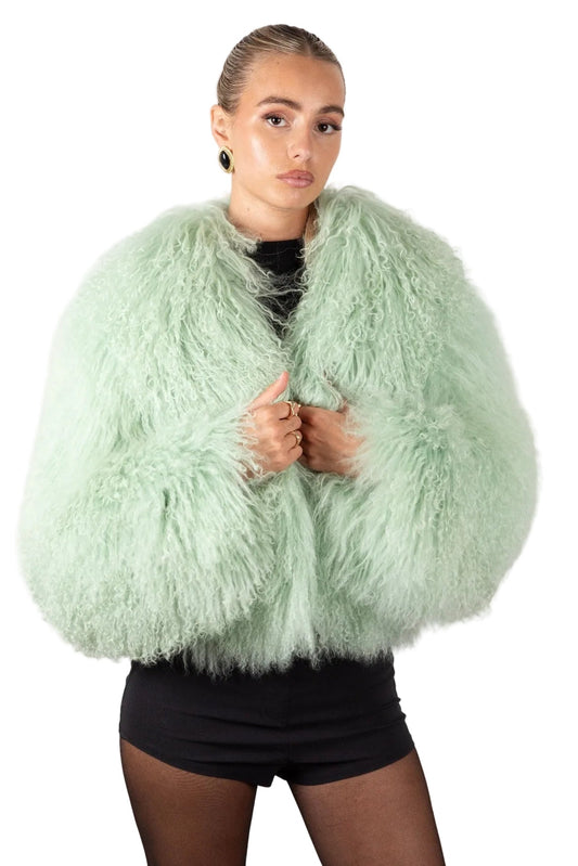 Person wearing a light gree mongolian fur jacket on a white background
