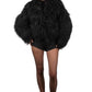 Person wearing a Black Mongolian fur coat over a black outfit on a plain background
