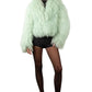 Person wearing a light green Mongolian  fur coat against a white background