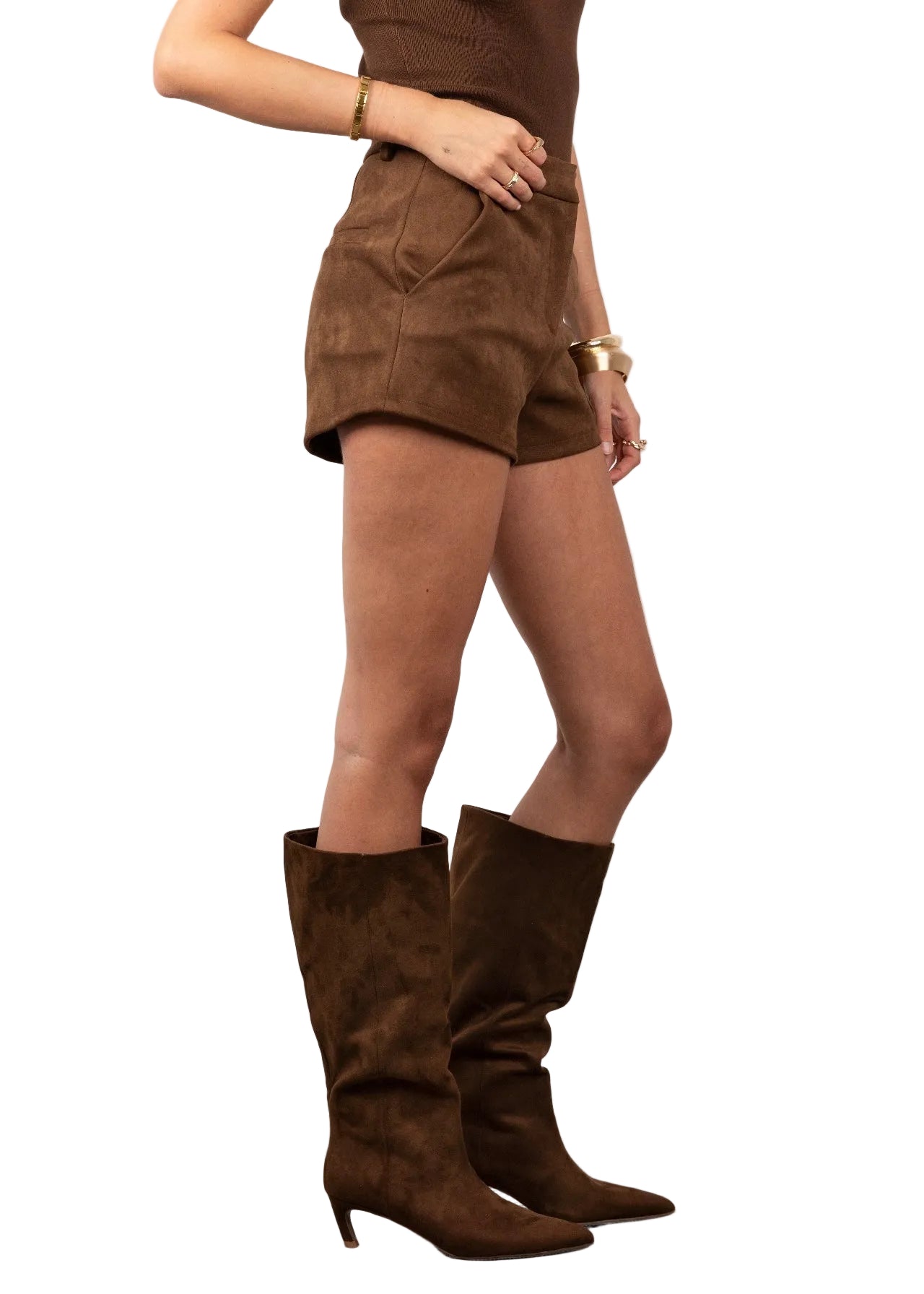 Person wearing brown suede boots, shorts, and top on a plain background