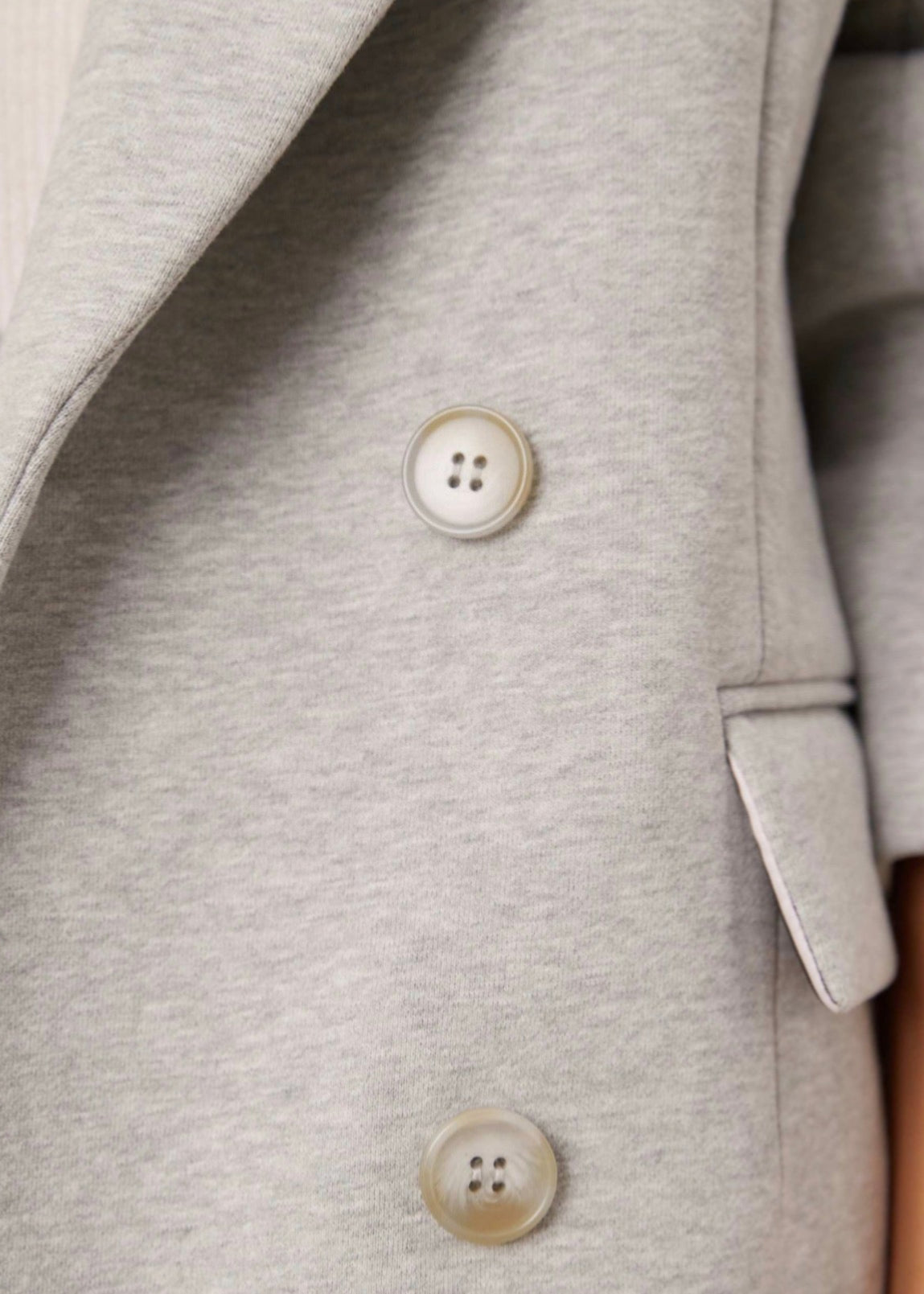 Close-up of a gray blazer with buttons on a plain background