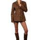 Woman wearing a brown suede blazer, skirt, and knee-high boots against a white background